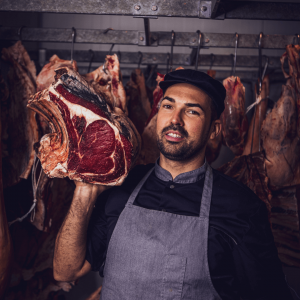 Photographie du patron de la Boucherie des Grèses avec des entrecotes